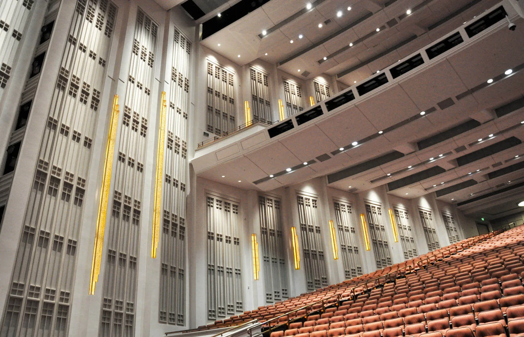The LDS Conference Center hall: tall paneled walls with vertical lights, a balcony front and tiered seating